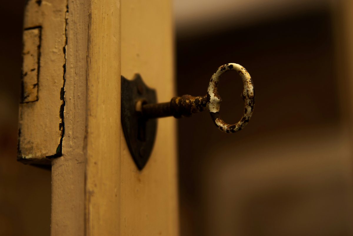 An antique key resting in the lock of an old cabinet — the access and ownership your business should hold over its own IT environment